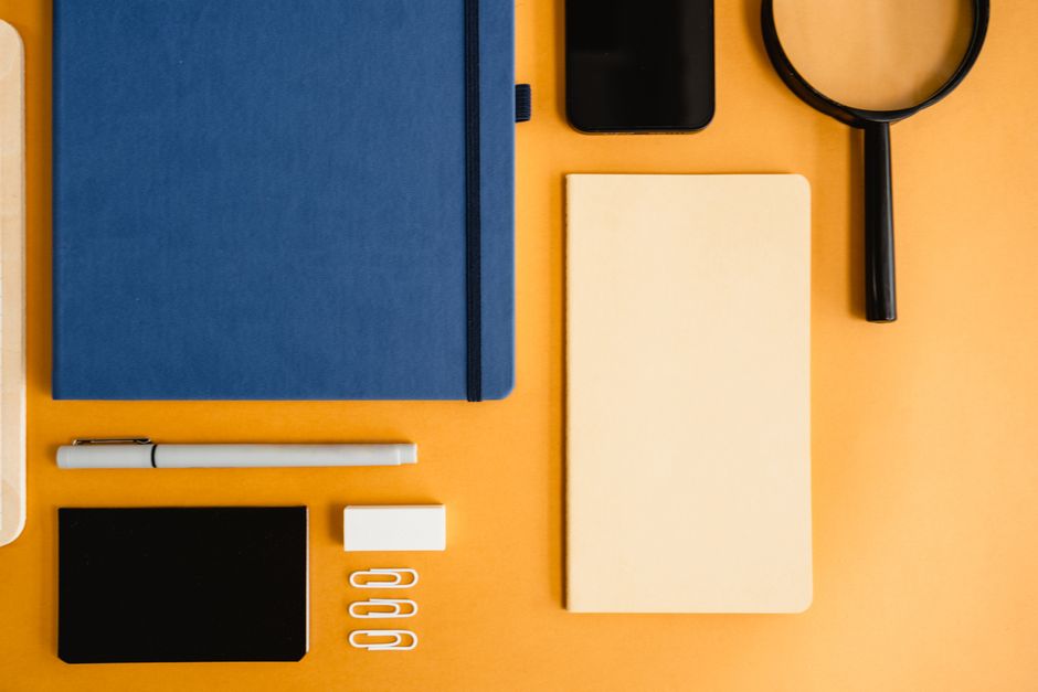 Artistic flat lay of diverse office stationery on a vibrant yellow background.