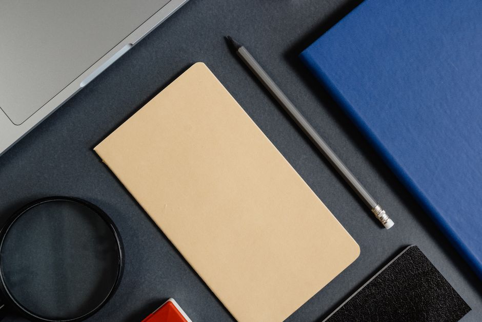 Flat lay of office stationery items with a minimalist design on a dark background.