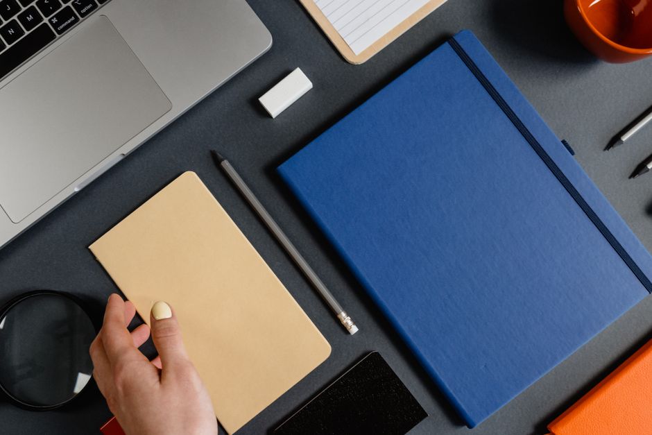 Flat lay of a modern workspace featuring notebooks, stationery, and a laptop for productivity.